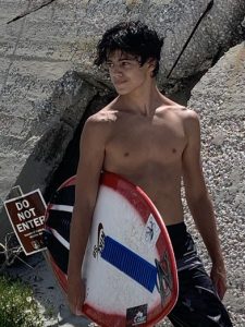 Logan posing with a skim board on the beach