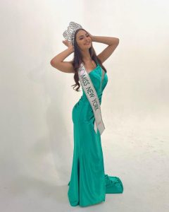 Nicole posing in a crown, gown, and sash that displays her winning title