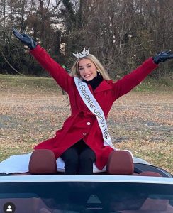 Rachel wearing her crown and sash in a car at a parade