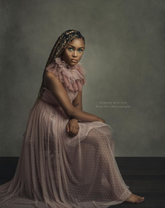 modeling shot of Chatayana seated looking serious and wearing a pink long dress