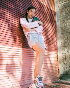 photo of Lily modeling in front of a garage and holding a purse