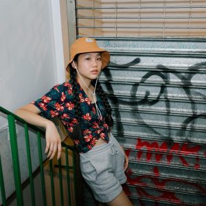 Lily modeling against a stair case in urban wear next to a graffitied wall