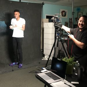 Roy behind the camera laughing while on set with a Barbizon actor who is also laughing 