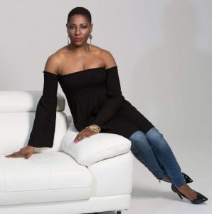 Yemi looking professional in a seated model's pose on a white couch