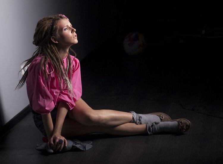 Girl posing seated on the floor looking at camera